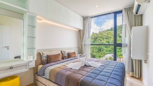 Ein Schlafzimmer mit einem großen Bett, einer Glasvitrine und Blick auf Grünflächen.
