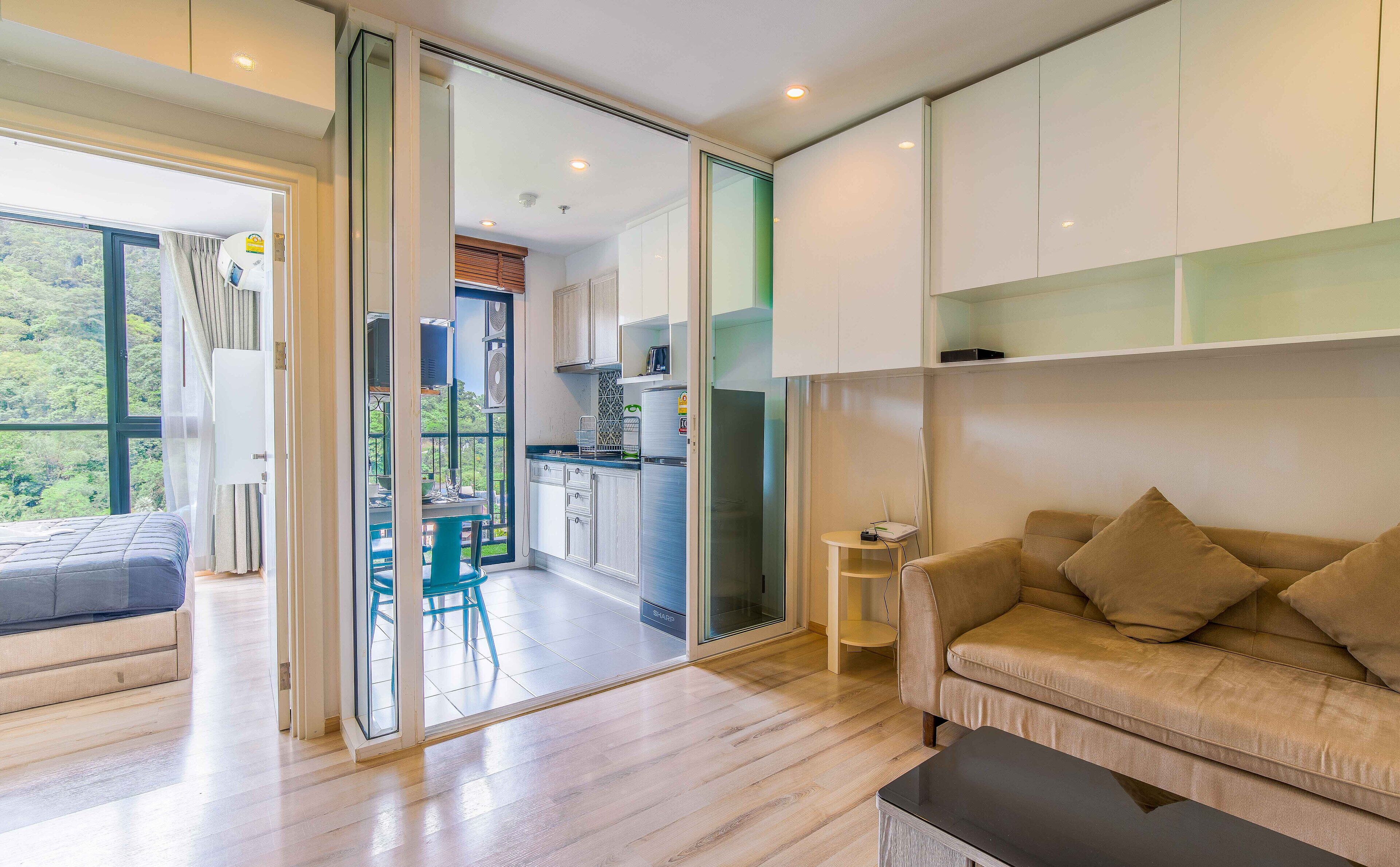 A modern living room with a sofa, a coffee table, and a view of a balcony with a dining area.