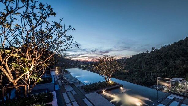 Ein modernes Hotel mit einem Infinity-Pool, Liegestühlen und Blick auf die umliegenden Hügel.
