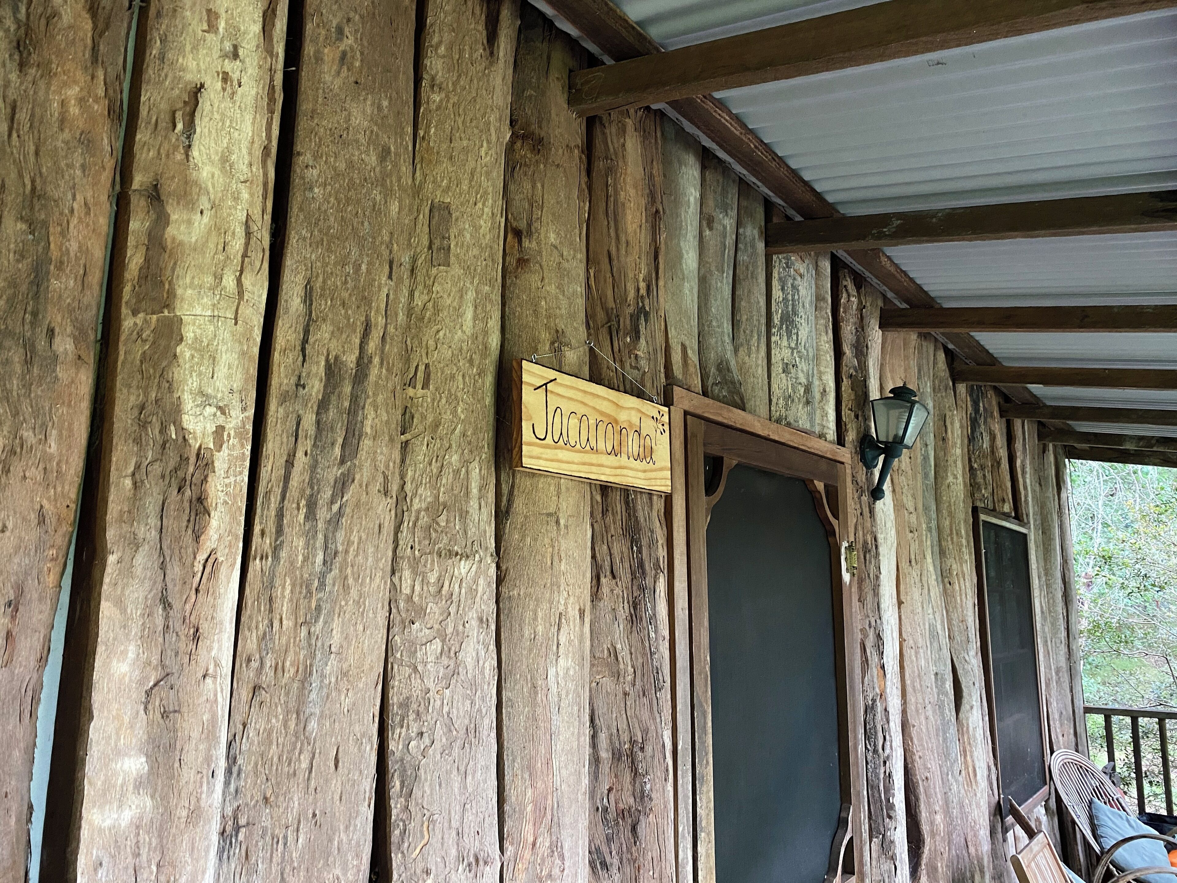 Une cabane en bois rustique, sur laquelle est accrochée une enseigne portant l’inscription « Jacaranda ».