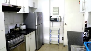A compact kitchen with white cabinets, a stainless steel stove, a refrigerator, and a microwave. - Miraflores Nest - Alcanfores (Miraflores)