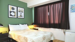 A bedroom with a bed, two bedside tables, a lamp, a wall-mounted air conditioner, and two framed pictures. - Miraflores Nest - Alcanfores (Miraflores)