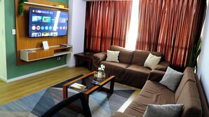 A living room with a sofa, a coffee table, a TV mounted on the wall, and a curtain. - Miraflores Nest - Alcanfores (Miraflores)