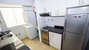 A kitchen with white cabinets, a stainless steel refrigerator, a gas stove, and a built-in oven. - Miraflores Nest - Alcanfores (Miraflores)