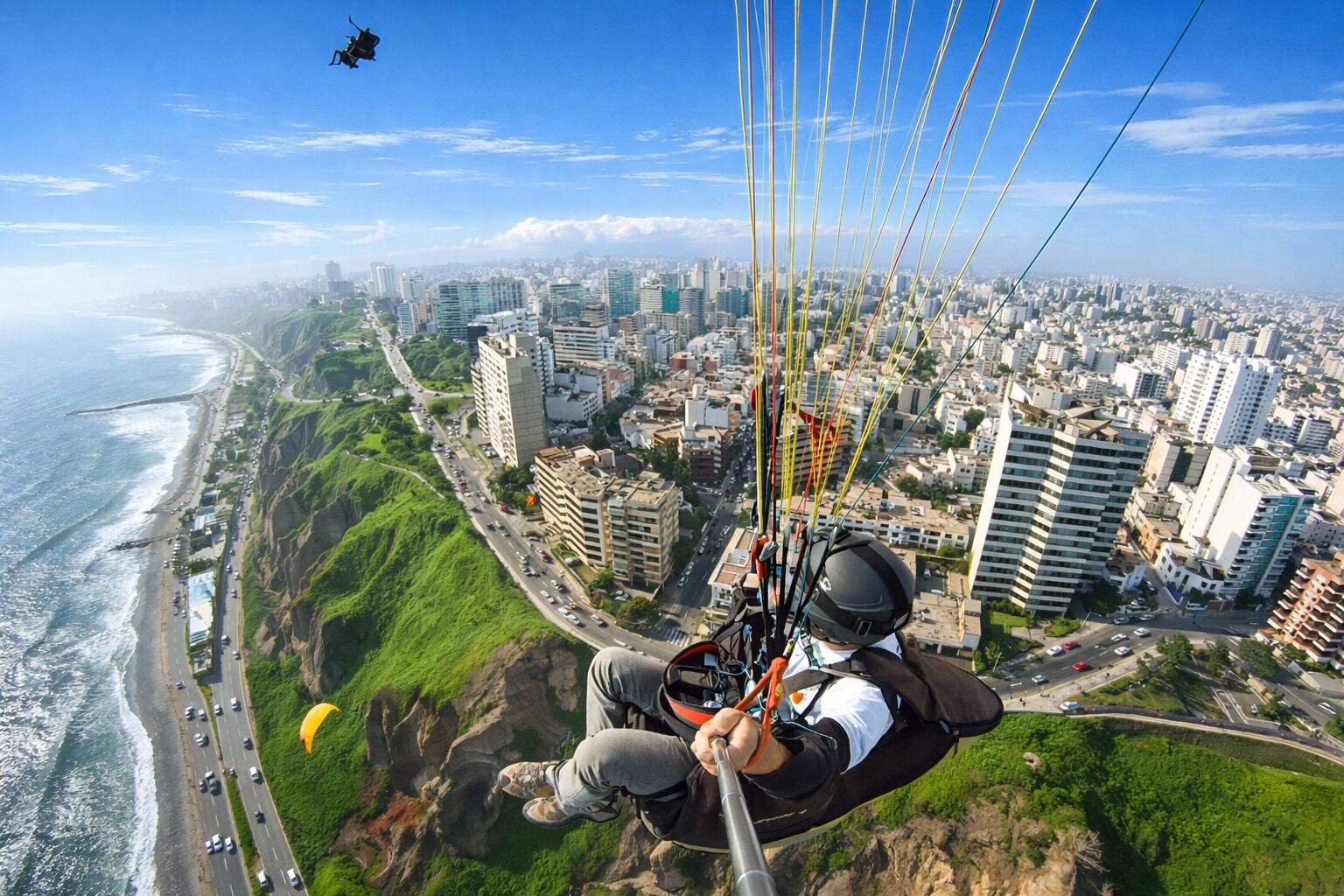 A person paragliding with a cityscape and coastline in the background.
