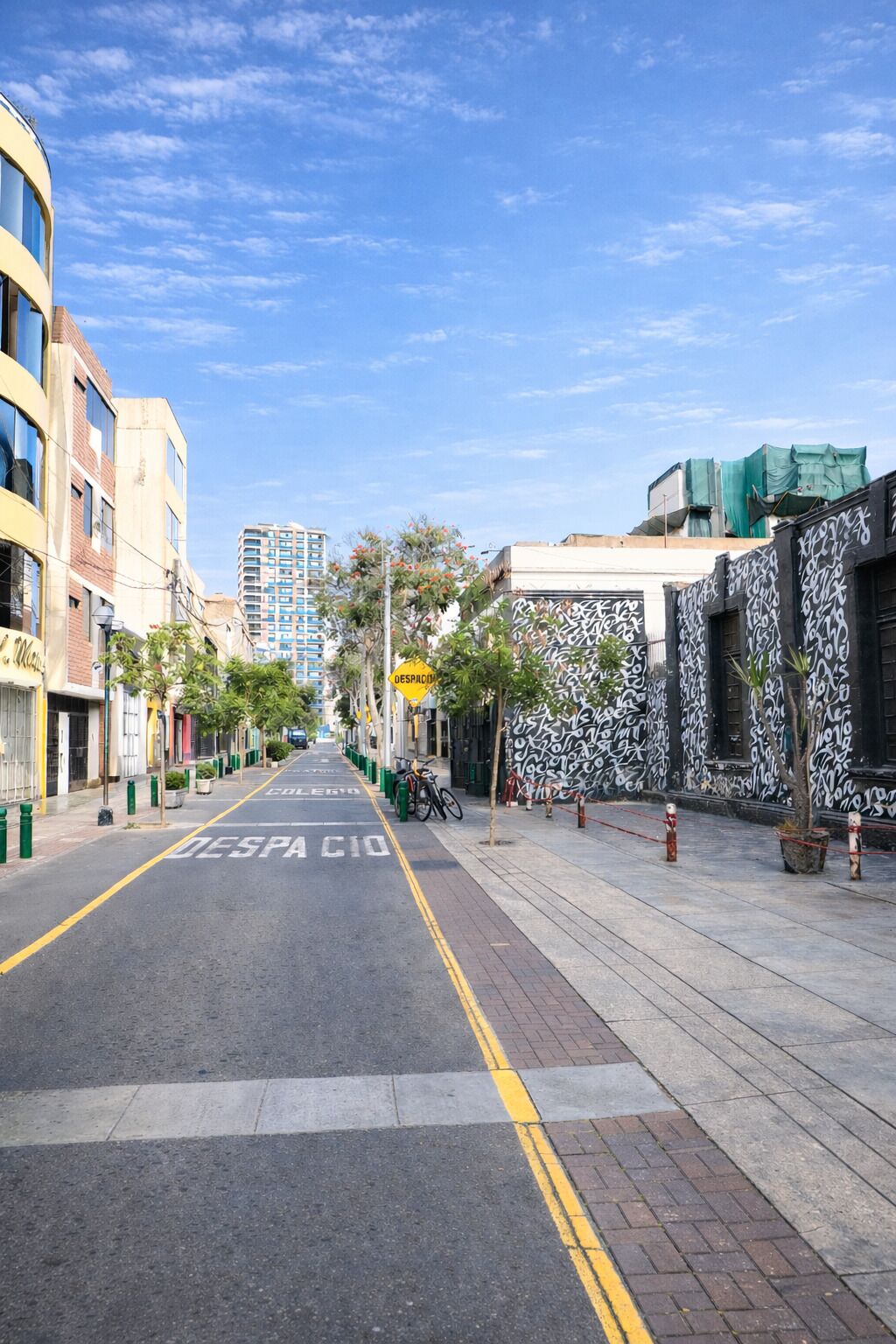 A street with a bike lane, buildings, and a clear sky.