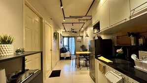 Une cuisine moderne avec un coin repas, dotée d’appareils électroménagers en acier inoxydable, d’un plan de travail noir et d’un design minimaliste.