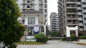 Un immeuble résidentiel à plusieurs étages, doté de balcons et d’une entrée sécurisée par un portail.