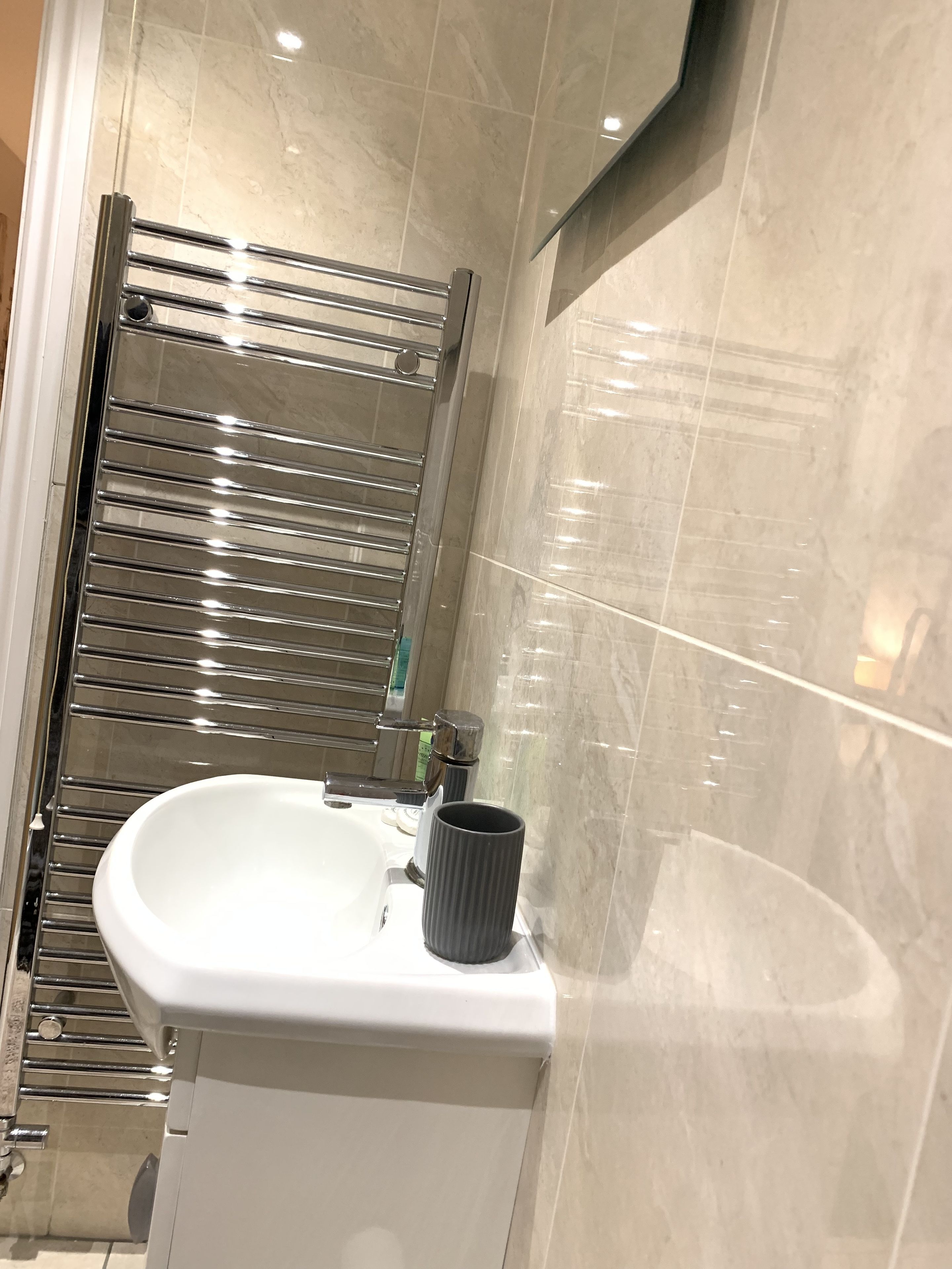 A bathroom with a white sink, a towel rack, and a mirror.
