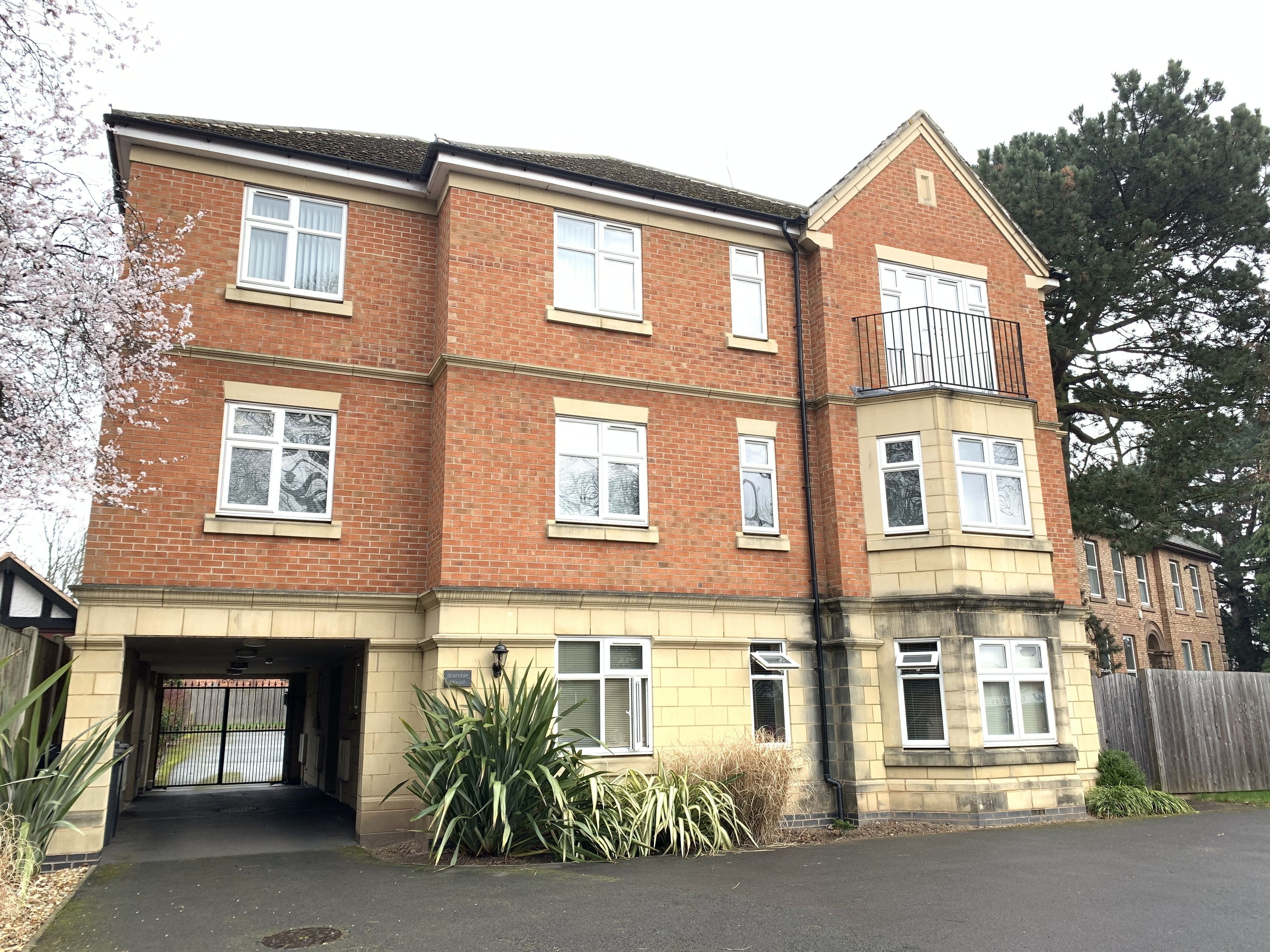 A two-story residential building with a garage entrance, multiple windows, and a small balcony.