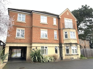 A two-story residential building with a garage entrance, multiple windows, and a small balcony.