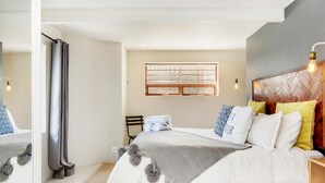 Quarto moderno com uma cama grande, cabeceira de madeira e janela com vista.