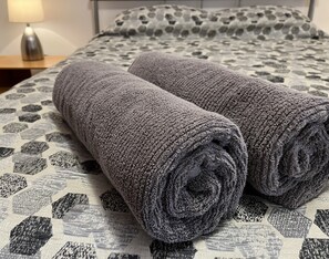 Two rolled towels on a bed with a patterned bedspread. - Relax at "Kangaroo Pause" @ Clayton Bay (Clayton Bay)