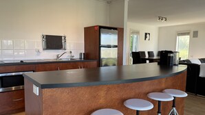 A modern kitchen with a central island, bar stools, a refrigerator, and a coffee machine. - Relax at "Kangaroo Pause" @ Clayton Bay (Clayton Bay)