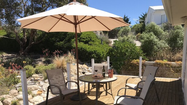 An outdoor patio with a round table, two chairs, a beige umbrella, and a bottle of wine. - Relax at "Kangaroo Pause" @ Clayton Bay (Clayton Bay)