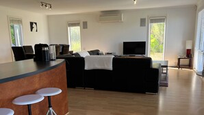 A modern living room with a black sofa, a TV, and a coffee station. - Relax at "Kangaroo Pause" @ Clayton Bay (Clayton Bay)