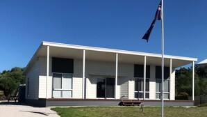 A single-story building with a porch, a flagpole, and a bench. - Relax at "Kangaroo Pause" @ Clayton Bay (Clayton Bay)