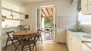 A kitchen with a dining area, a window, and a view of the outdoors. - Holiday home next to orange tree orchard, 185 sq.m with pool (ΒΟΧΑΣ - ΒΡΑΧΑΤΙΟΥ)