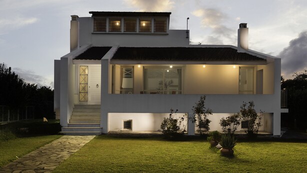A modern two-story house with a well-lit entrance and a visible staircase leading to the upper floor. - Holiday home next to orange tree orchard, 185 sq.m with pool (ΒΟΧΑΣ - ΒΡΑΧΑΤΙΟΥ)