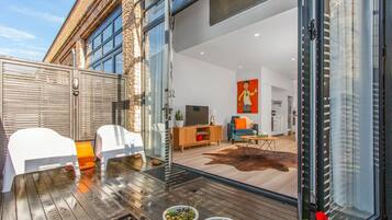 A modern living room with a glass door leading to a kitchen and dining area.