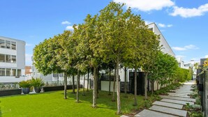 A modern residential area with a well-maintained lawn, a pathway, and a row of trees. - City Fringe Converted Industrial Townhouse (Auckland)