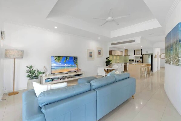 Uma sala de estar moderna com sofá, TV e área de jantar.