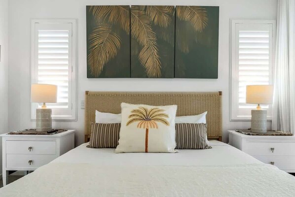 A bedroom with a bed, two nightstands, a woven headboard, and a wall-mounted artwork.