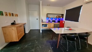 Una cocina compacta con microondas, horno y un refrigerador rojo. Se observa un mueble de madera y una encimera blanca.