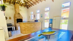 Una cocina amplia con horno de ladrillo, una isla central con un cuenco decorativo y un ventilador de techo.