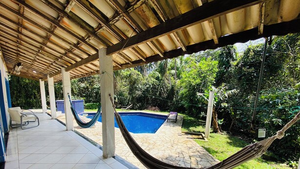 Un patio techado con piscina, una hamaca y una silla.