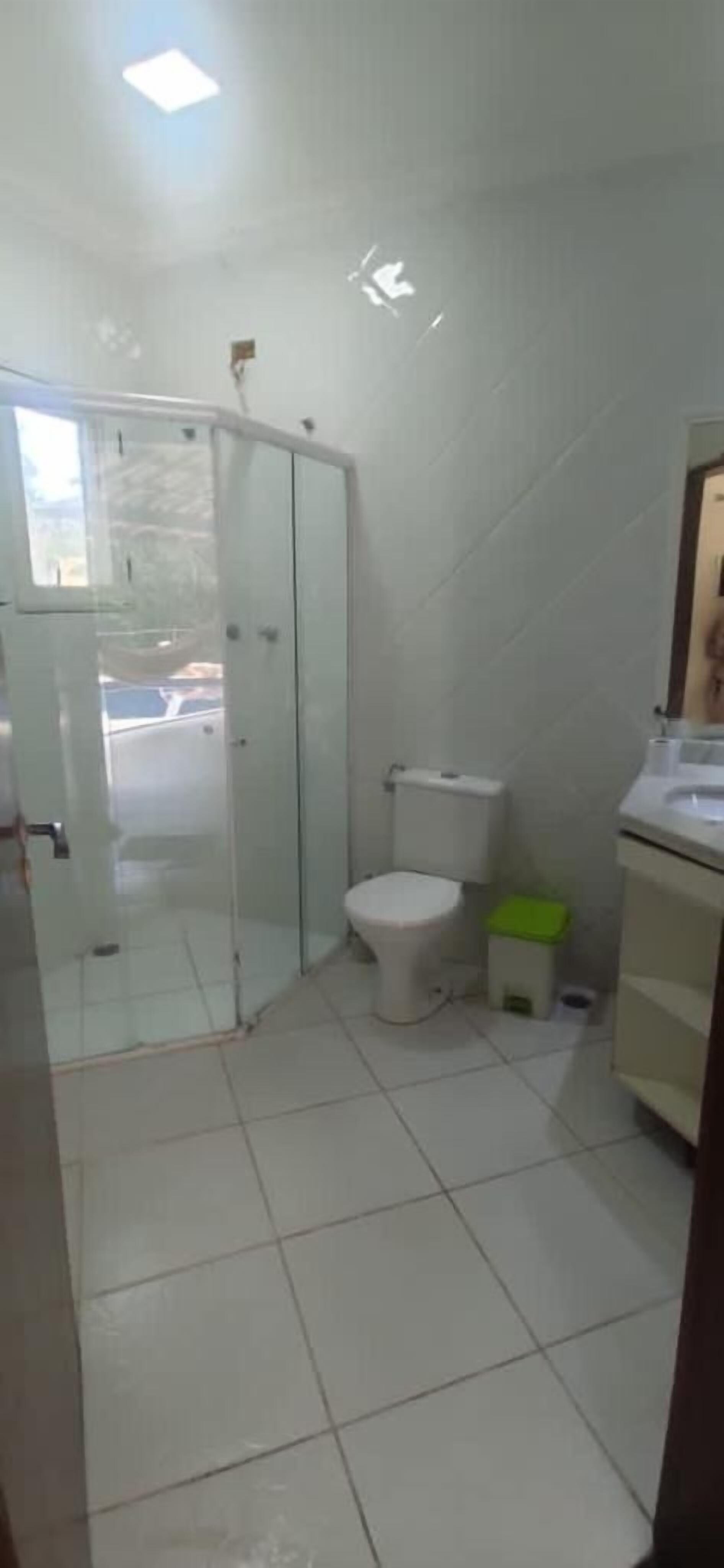 A bathroom with a toilet, a small trash bin, and a glass shower enclosure.