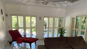 Un amplio salón con un sofá seccional grande, un sillón rojo y un ventilador de techo.