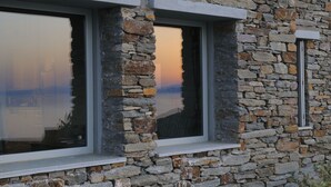 Ein Steinhaus mit drei Fenstern, jeweils mit weißem Rahmen.