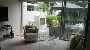 Una sala de estar moderna con una mesa de vidrio, un sofá de mimbre y un sillón cómodo.