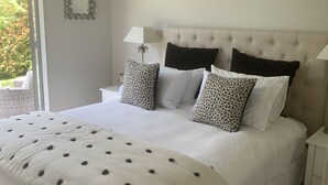Un dormitorio con una cama grande, una mesita de noche, una lámpara y un espejo en la pared.