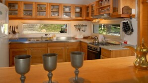Una cocina con armarios de madera, un lavamanos de acero inoxidable y una estufa.