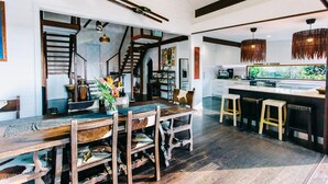 A spacious kitchen with a central island, wooden chairs, and a staircase leading to an upper level. - BELLINGEN CONVERTED CHURCH on the river (Fernmount via Bellingen)