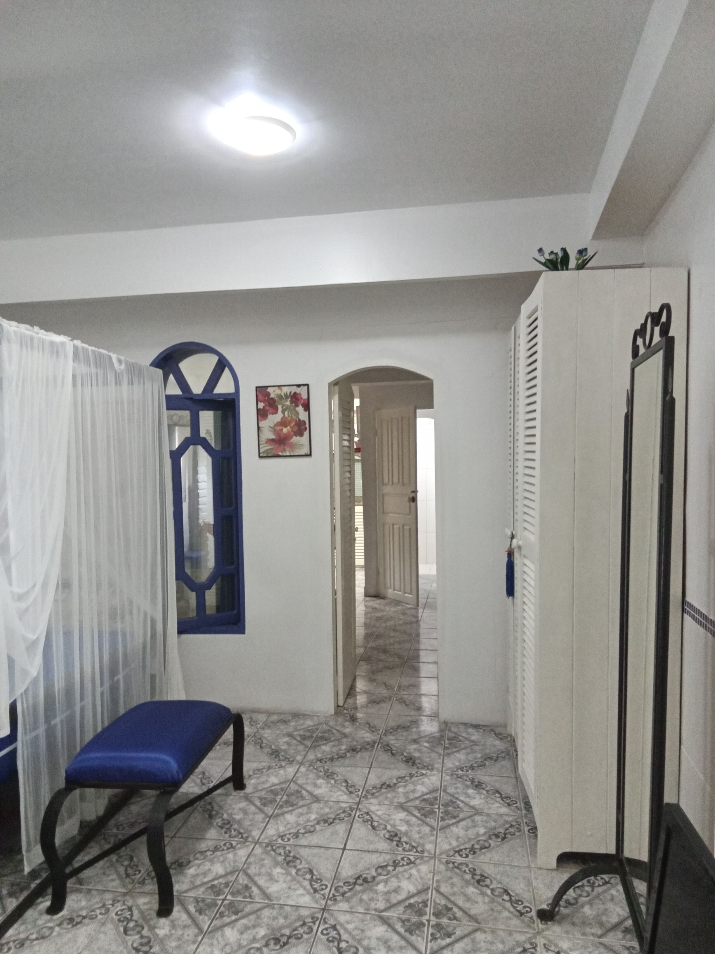 Un pasillo con un banco, un armario y una puerta que da a otra habitación.