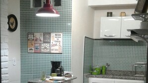 Une cuisine compacte avec un plan de travail recouvert de carreaux, un petit îlot central doté de tabourets et un four à micro-ondes.