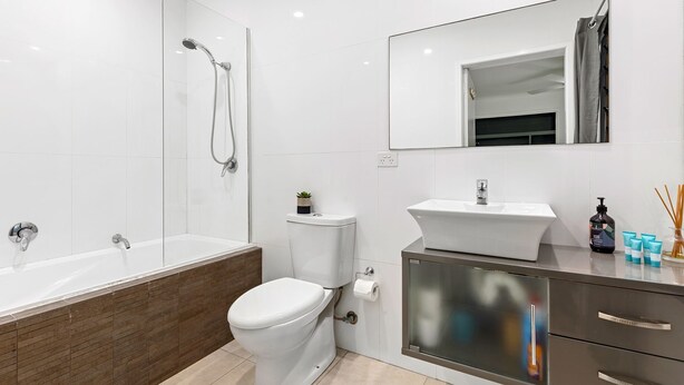 Un baño moderno con bañera, inodoro, lavamanos y espejo.