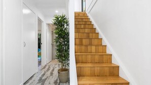 Um interior moderno com escada de madeira, corredor com piso estampado e planta em vaso.