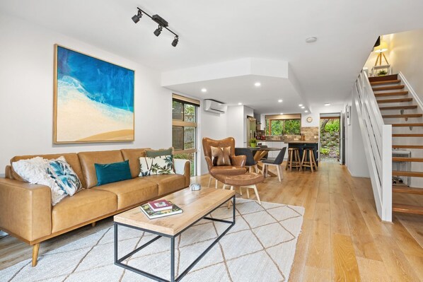 A spacious living area with a sofa, coffee table, and a large painting.