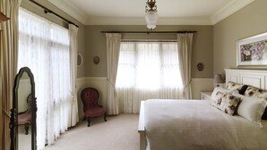 A bedroom with a large bed, a chair, and a mirror.