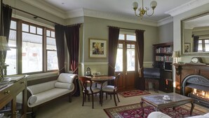 A traditional living room with a fireplace, a sofa, a dining table, and a bookshelf.
