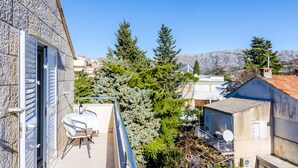 Un balcón con mesa y sillas, con vistas a una zona residencial con casas y árboles.