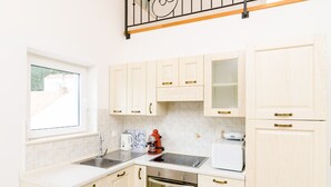 Una cocina con gabinetes de madera clara, un lavamanos de acero inoxidable, una cafetera y un tostador.