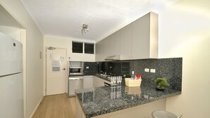 A modern kitchen with granite countertops, stainless steel appliances, and a small island with bar stools.
