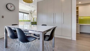 Een moderne keuken met een witte tafel, zwarte stoelen en een groene hanglamp.