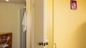 Ein Zimmer mit gelber Wand, weißer Tür und einem kleinen Bild an der Wand.