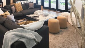 A modern living room with a sofa, ottomans, and a large lamp. - The Edge 13 Marine Parade, Newell Beach QLD 4873 (Newell)